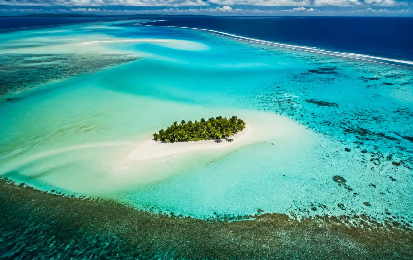 Palmengesäumter weißer Sandstrand mit türkisfarbenem Wasser auf den Cook Islands – Inselflitterwochen im Südpazifik