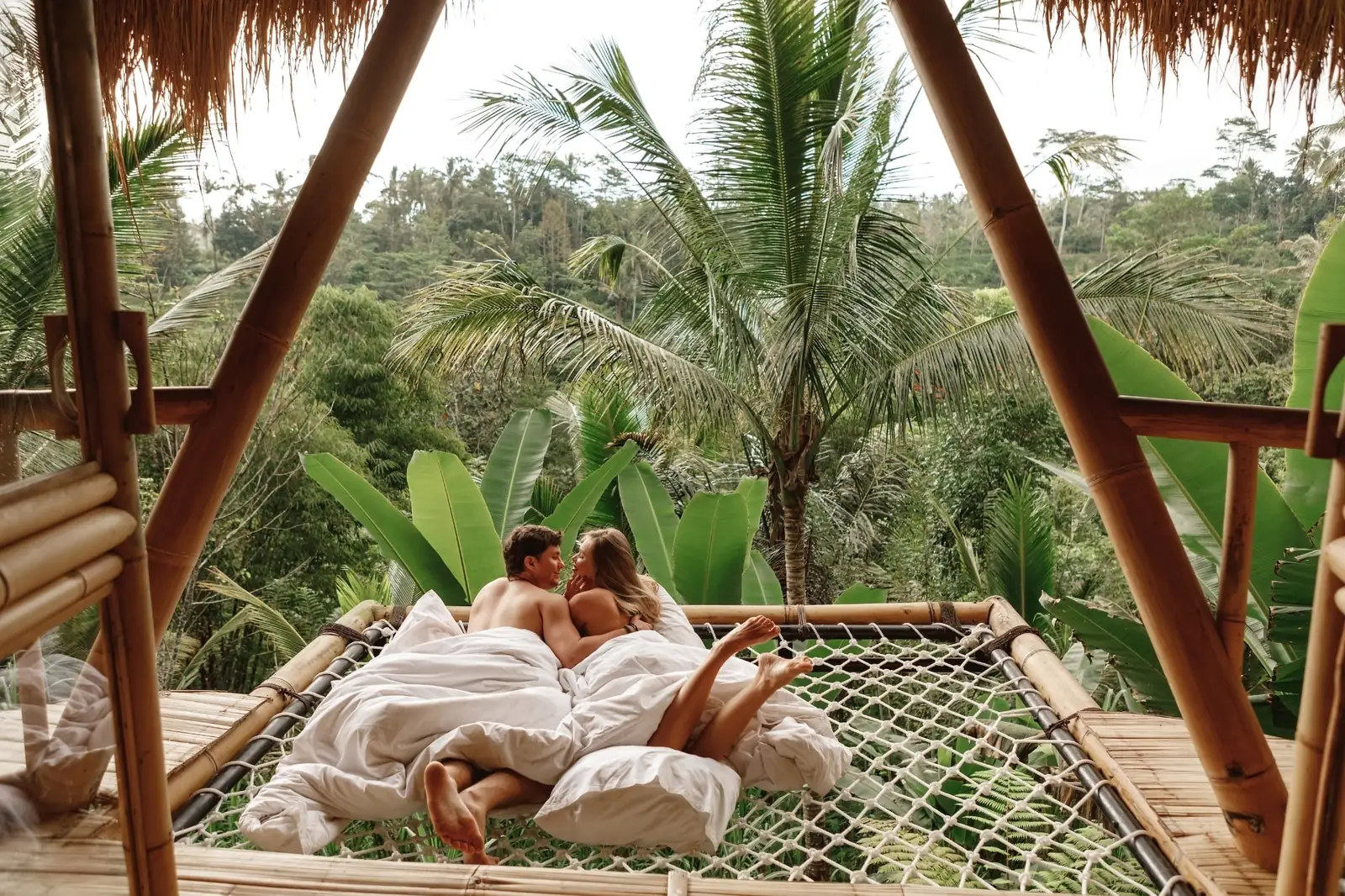 Frisch vermähltes Paar entspannt im Bambus-Netzbett einer Dschungelvilla über dem Regenwald von Ubud auf Bali, Indonesien